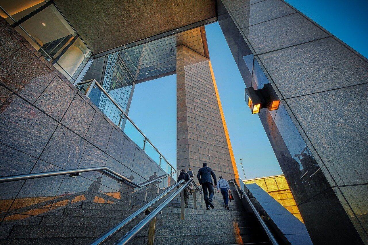 People walking up the skyscraper entrance stairs
