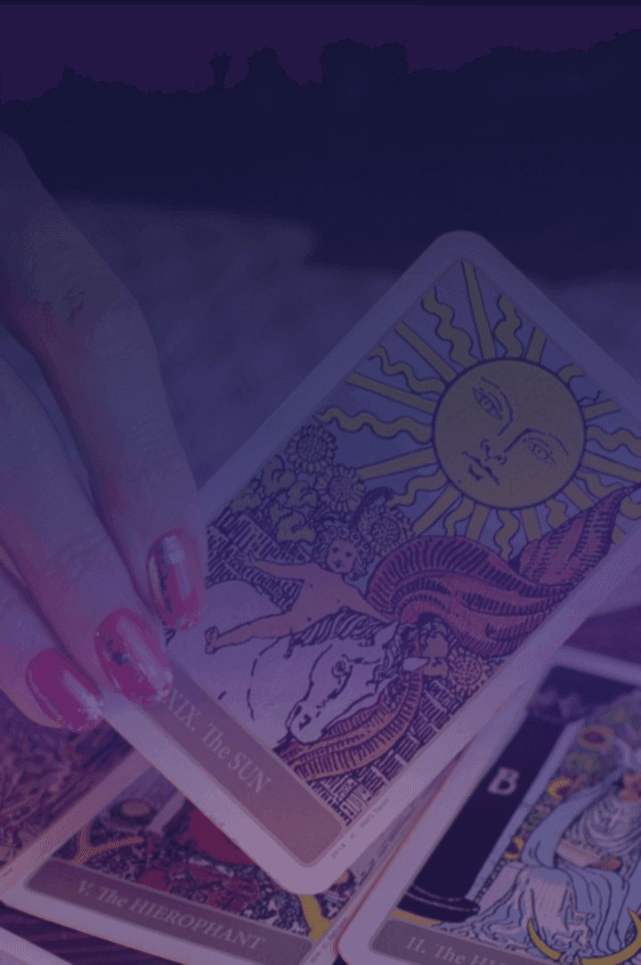woman's hand holding holding a tarot card over a table with other tarot cards laid out