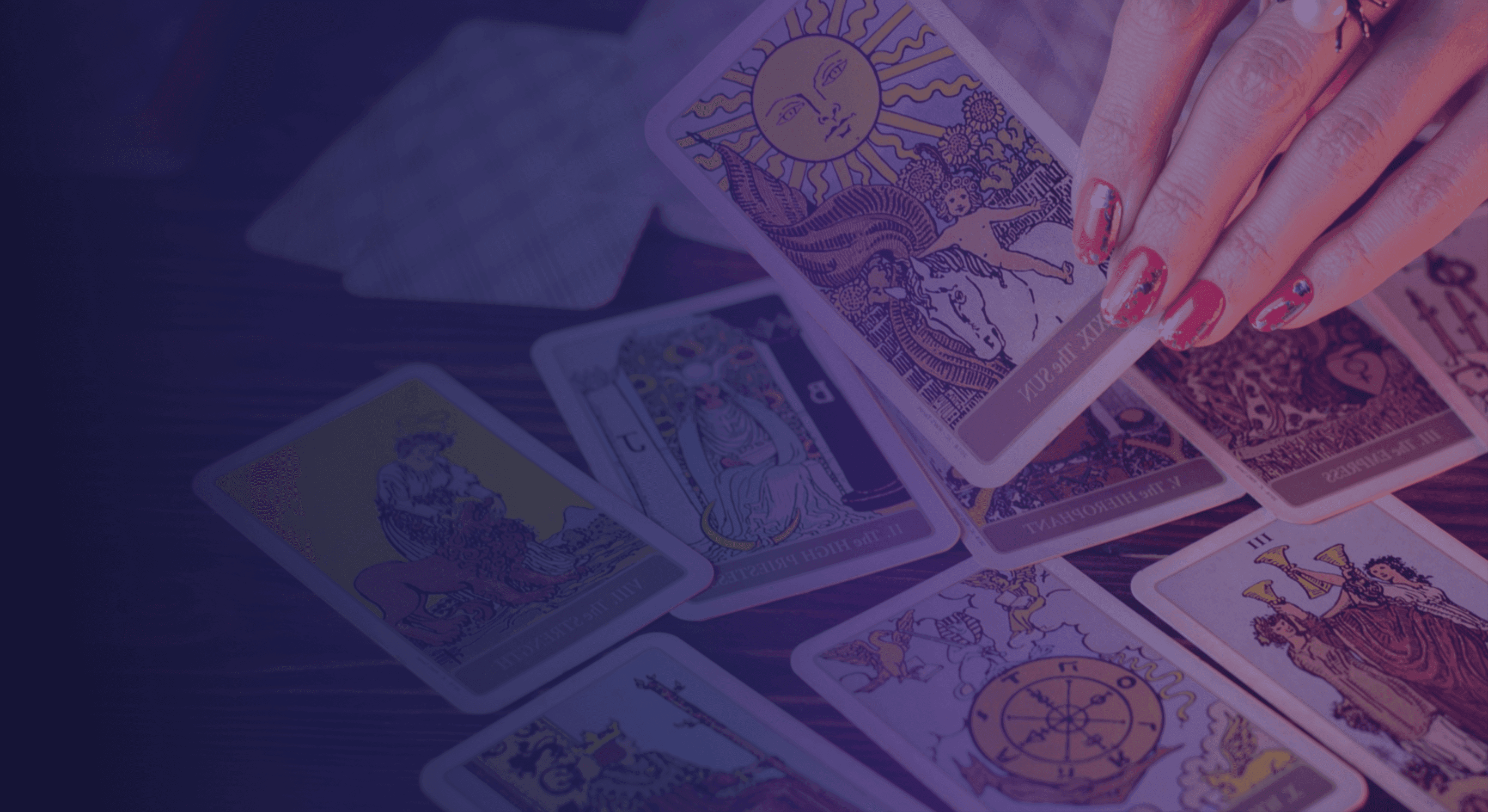 woman's hand holding holding a tarot card over a table with other tarot cards laid out