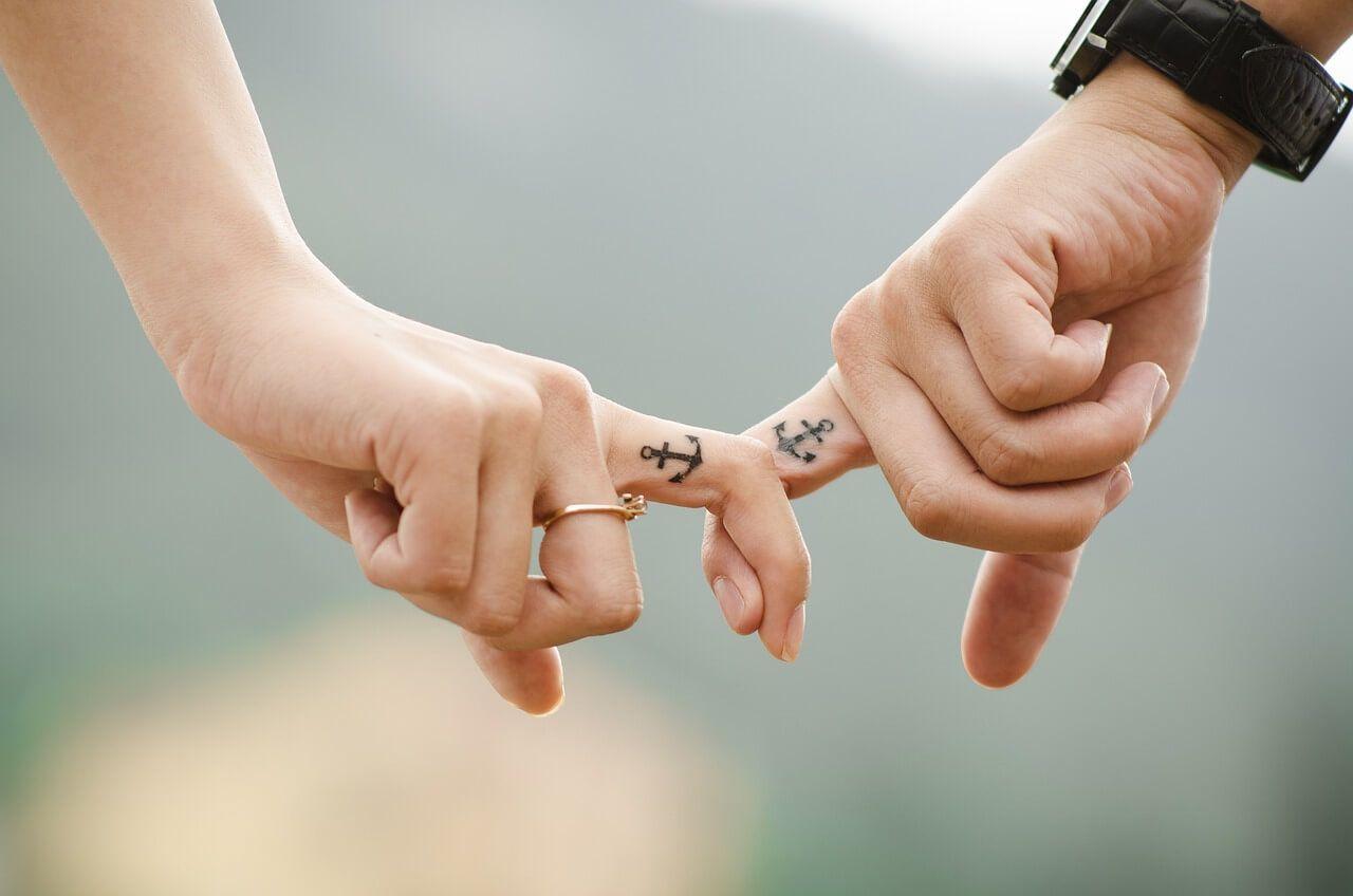 two people holding hands, holding each other by their index fingers